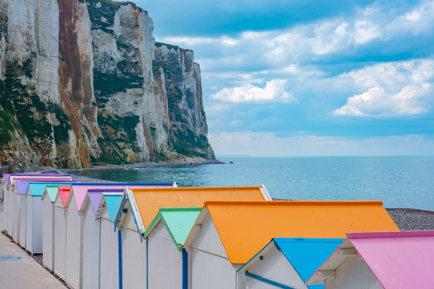 Bunte Strandhäusschen vor weißen Klippen an der Alabasterküste Normandie
