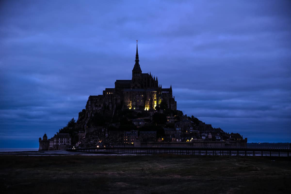 Ein teils beleuchteter Mont Saint Michel nach Einbruch der Dunkelheit